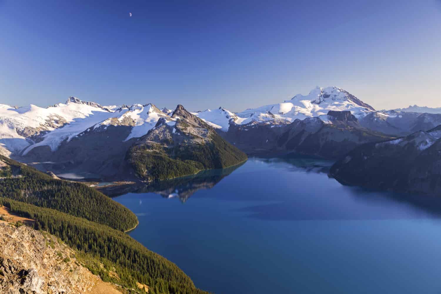 Vista panoramica del paesaggio del lago Blue Garibaldi e delle montagne della costa innevate lontane dalla cresta del panorama nel corridoio dal mare al cielo tra Squamish e Whistler, British Columbia Canada