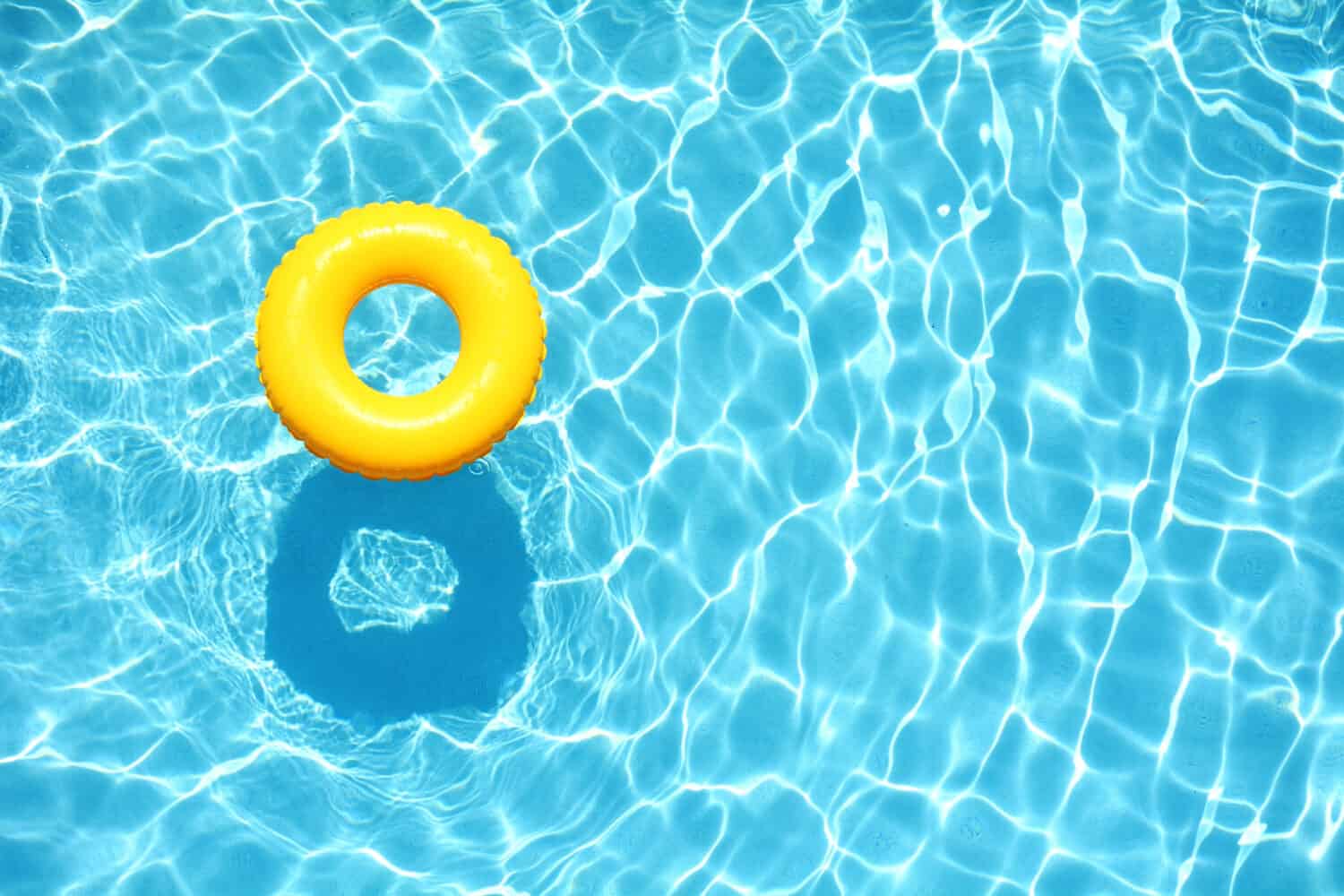 Galleggiante giallo per piscina, anello galleggiante in una rinfrescante piscina blu