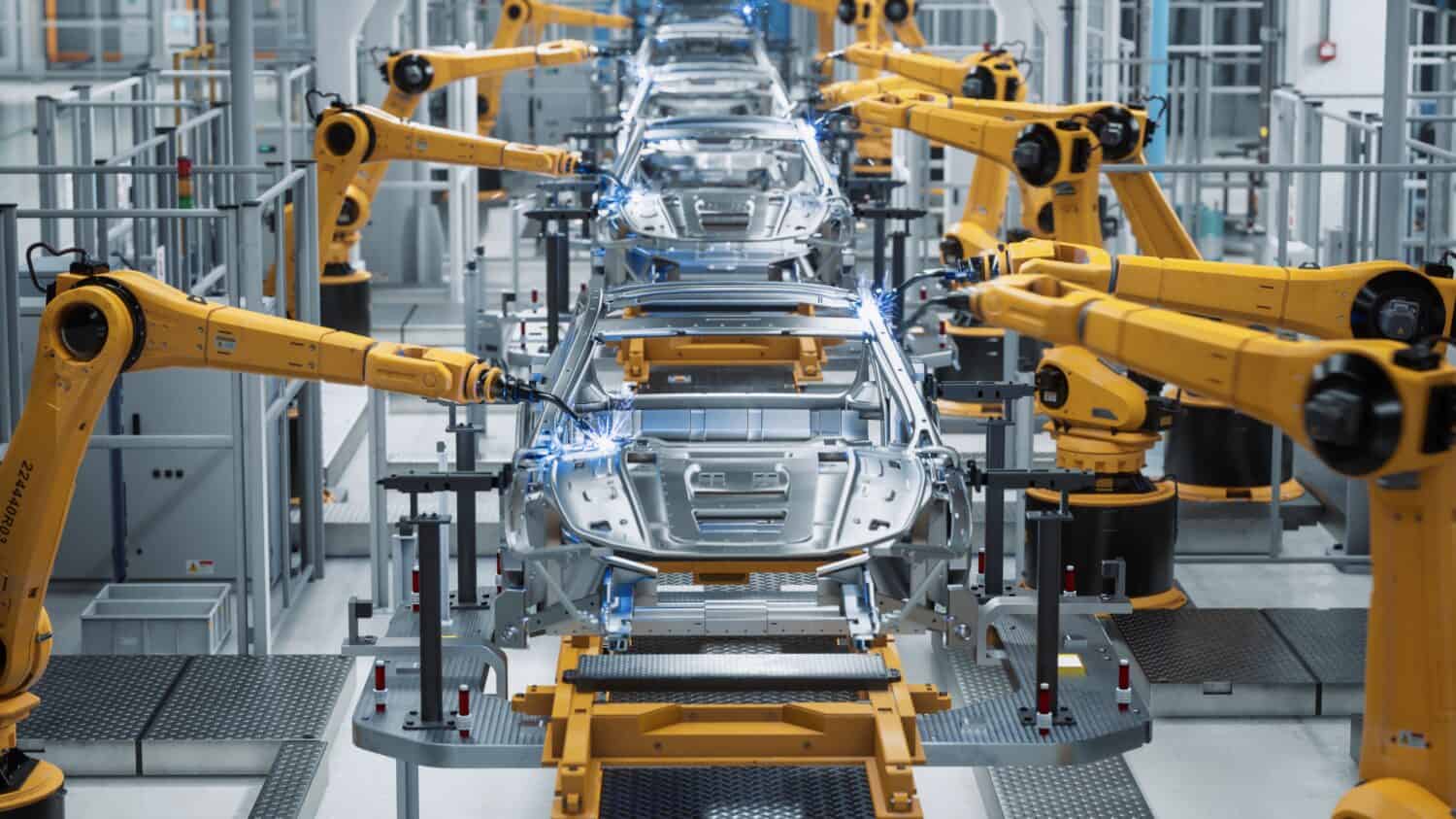 Concetto 3D di fabbrica di automobili: catena di montaggio automatizzata del braccio robotico che produce veicoli elettrici ad alta tecnologia a energia verde.  Costruzione automatica, edilizia, trasportatore di produzione industriale di saldatura.  Vista frontale