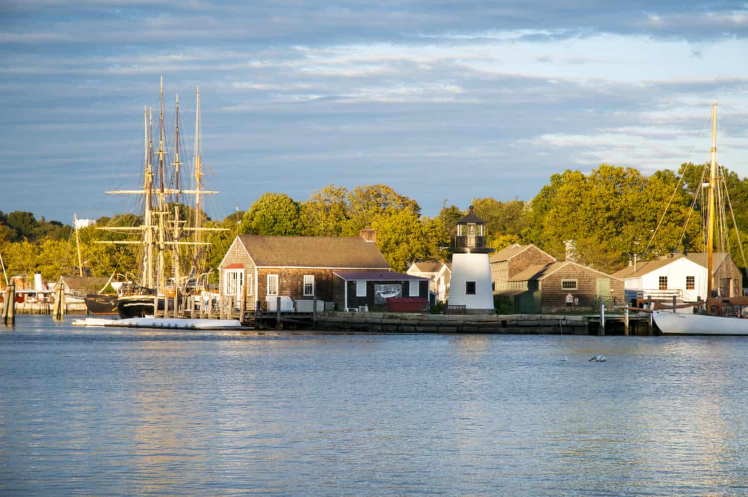 Tramonto di fronte a Mystic Seaport, un porto marittimo del XIX secolo ricreato all'aperto nel Connecticut.  I visitatori troveranno una nave baleniera e una replica della luce di Brant Point dall'isola di Nantucket.