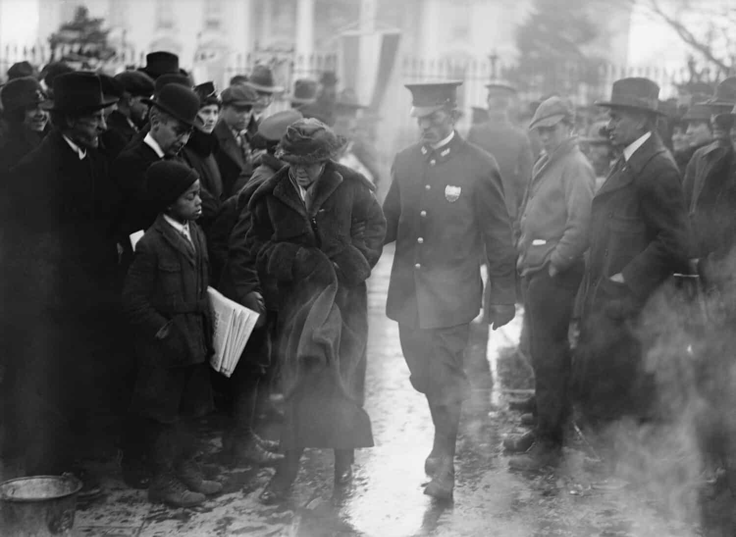 Un poliziotto conduce una manifestante del National Woman's Party arrestata lontano dalla dimostrazione del falò per il suffragio femminile alla Casa Bianca nel 1918.
