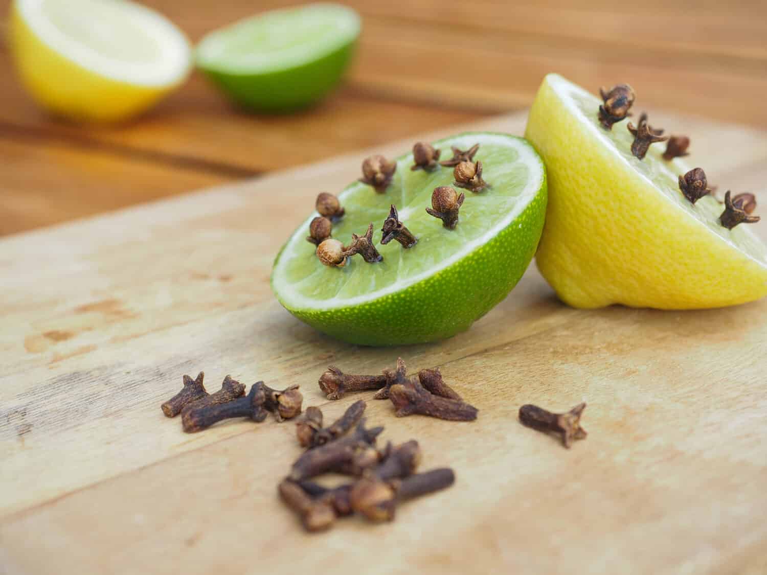 Repellenti naturali fatti in casa su tavola di legno.  Lime e limone con chiodi di garofano.