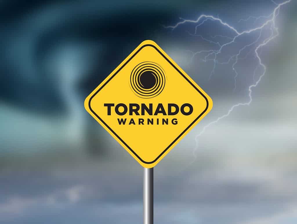 Segnale di avvertimento tornado contro un potente sfondo tempestoso con spazio per la copia.  Il cartello sporco e angolato con venti ciclonici si aggiunge al dramma.
