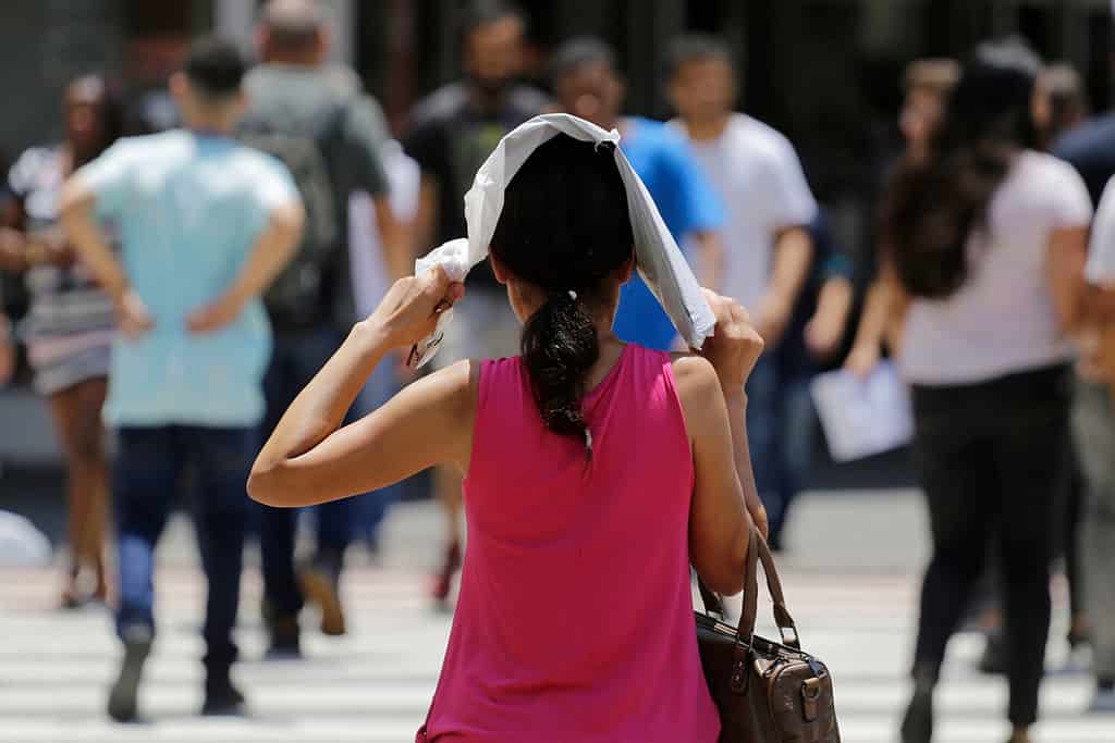 Una donna si protegge dal sole caldo mentre cammina in una strada del centro durante un'ondata di caldo estremo a San Paolo, in Brasile.