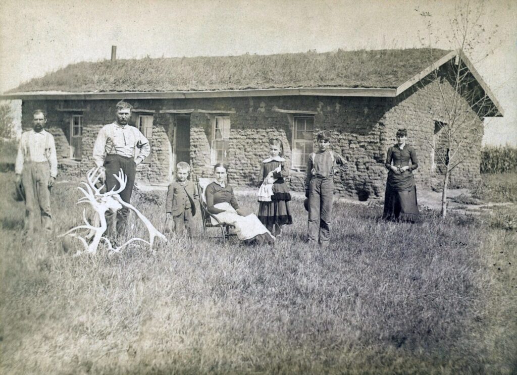 Famiglia Morrison davanti alla casa di zolle nella contea di Custer, Nebraska nel 1886. Il legname era spaventoso e le abitazioni di zolle furono la prima casa per molti pionieri.