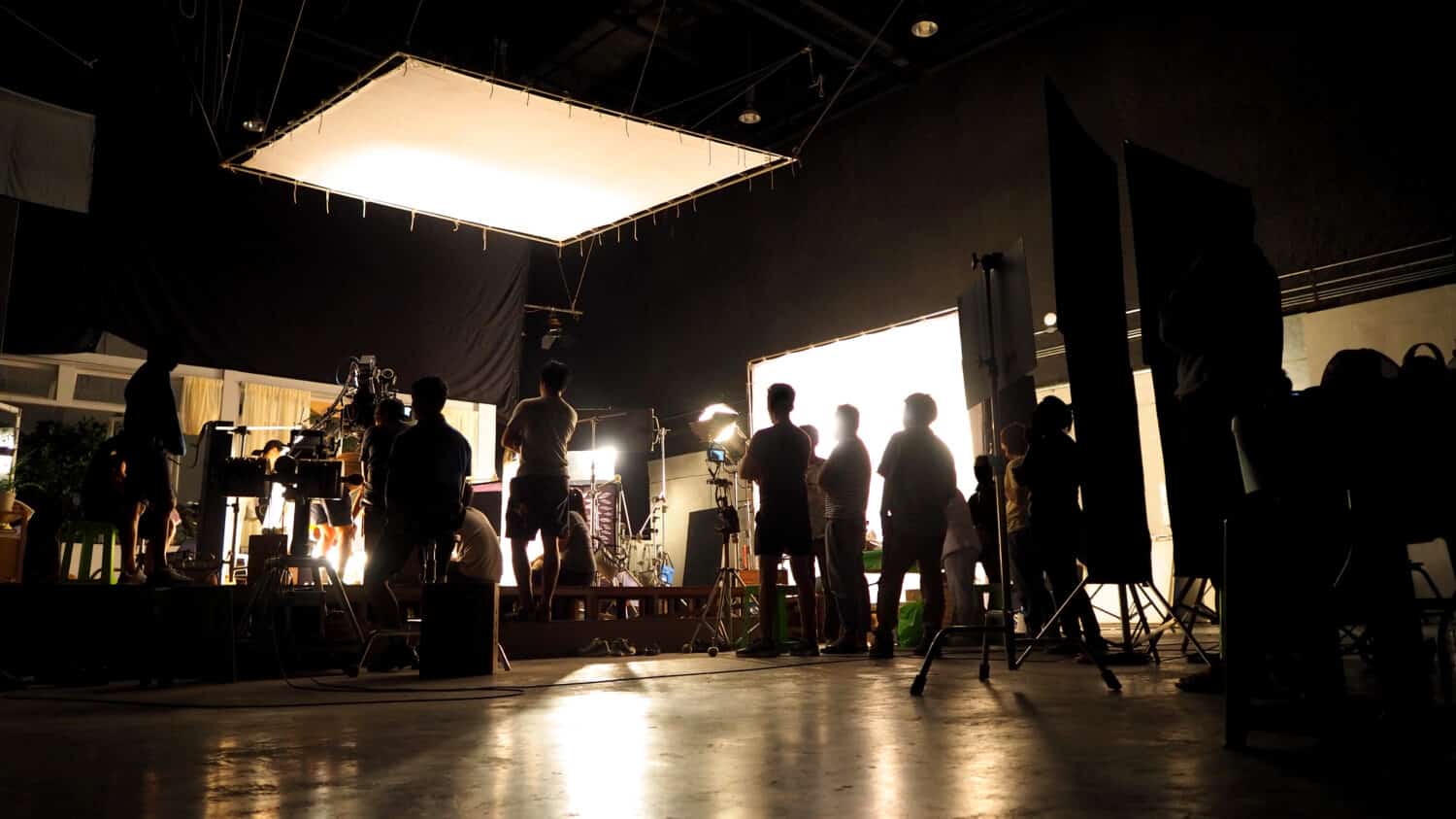 Dietro le quinte della troupe di produzione di riprese video silhouette del team e attrezzatura fotografica in studio. 