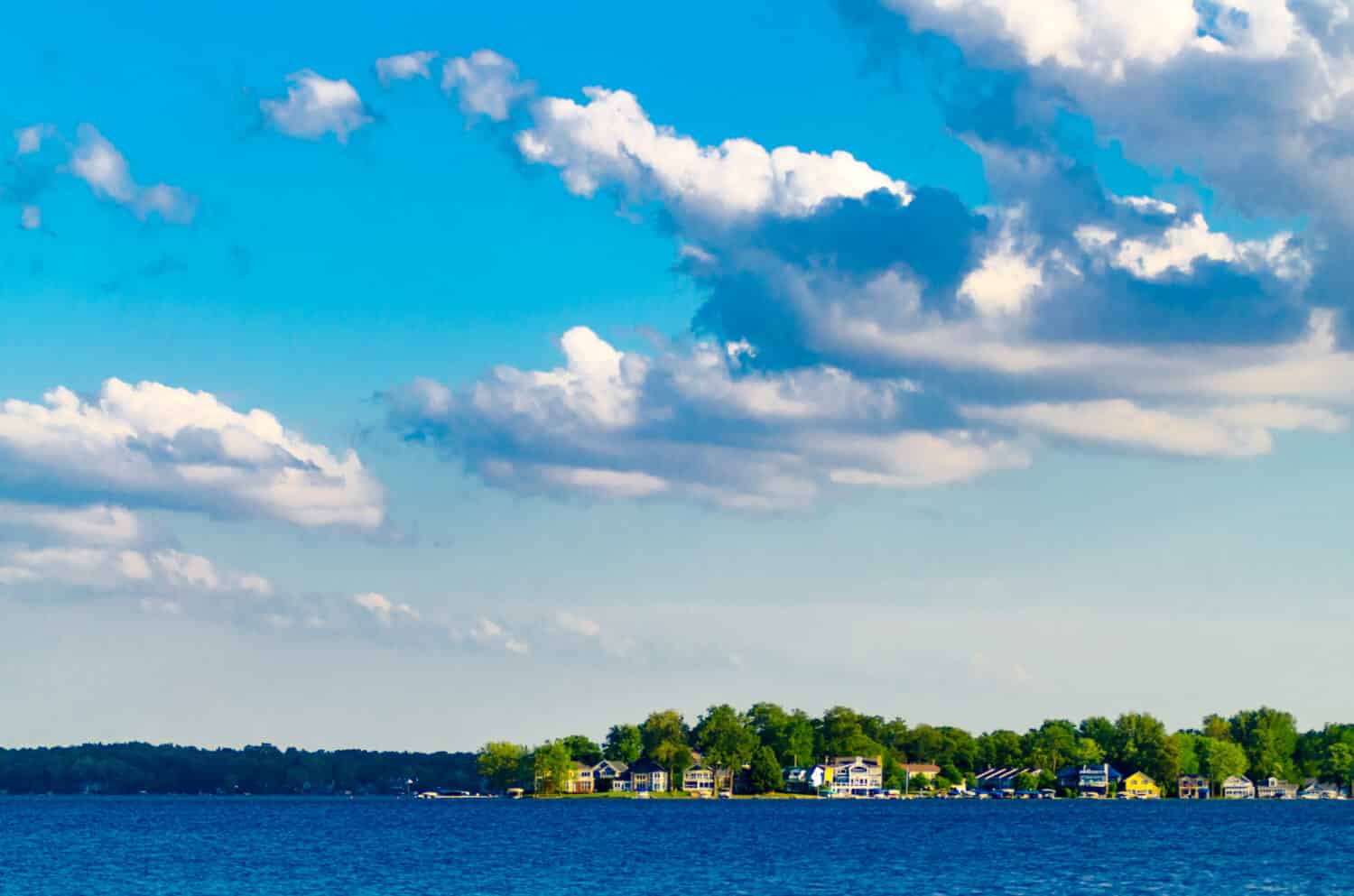 Le case per le vacanze fiancheggiano le rive del lago Maxinkuckee a Culver, nell'Indiana, mentre le nuvole bianche si stagliano contro un cielo blu