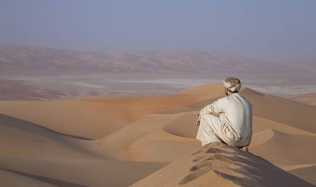 Uomo in abito tradizionale nel deserto del quarto vuoto che copre una vasta area degli Emirati Arabi Uniti, KSA e Oman