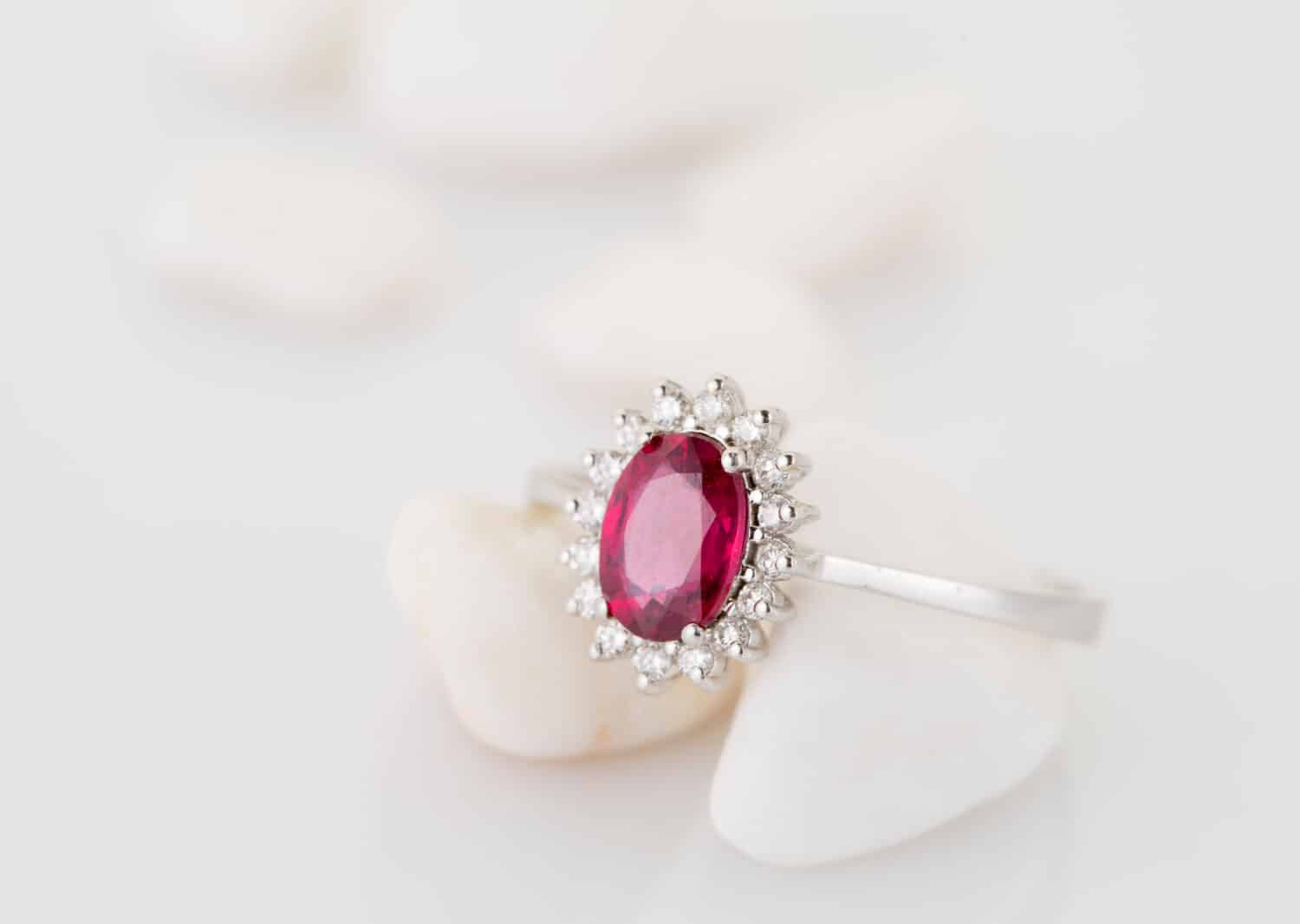 Anello con diamante topazio rosso (rubino) su sfondo bianco morbido.