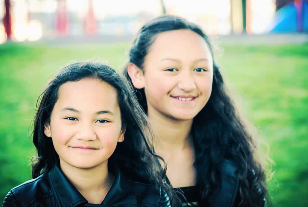 Ritratto di due giovani sorelle Maori scattate all'aperto in un parco.