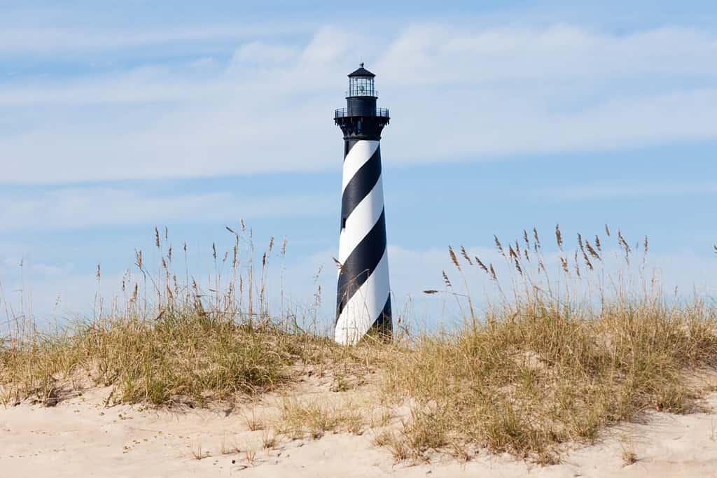 Il faro di Cape Hatteras domina le dune della spiaggia dell'isola di Outer Banks vicino a Buxton, North Carolina, USA