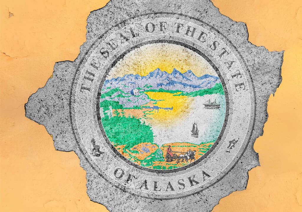 Bandiera del sigillo dello stato dell'Alaska degli Stati Uniti dipinta su foro di cemento e struttura della facciata della parete incrinata