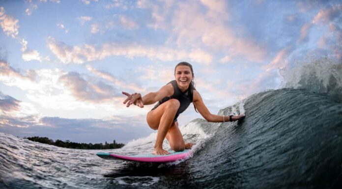 Giovane donna che pratica il surfing sulla tavola da surf rosa