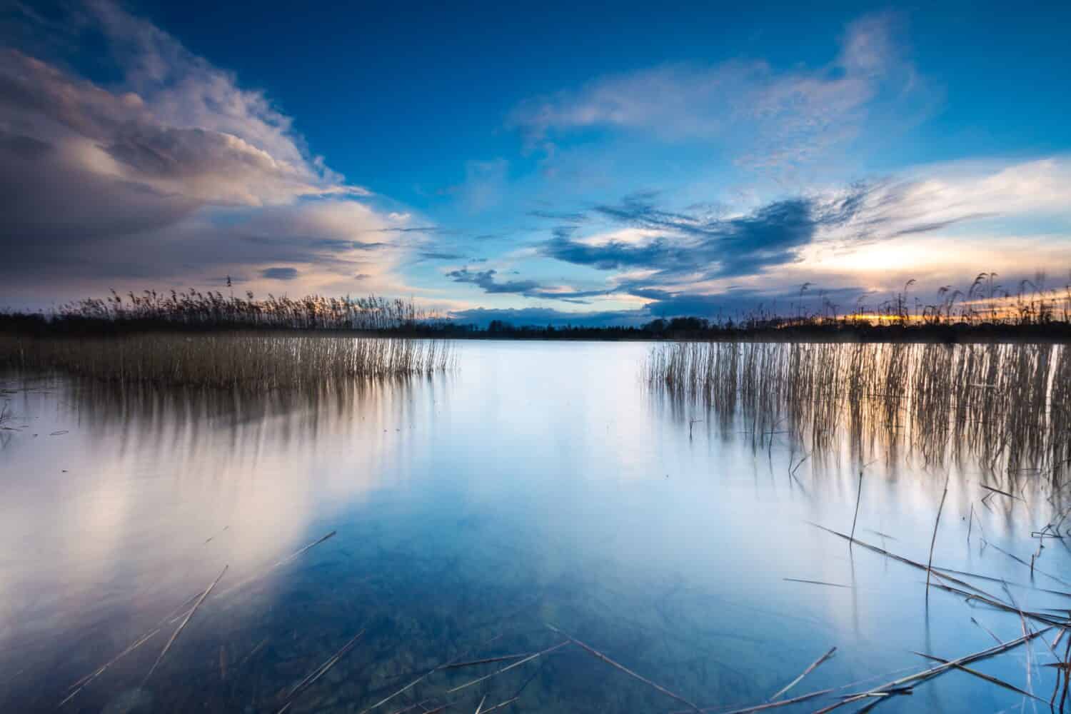 Bel tramonto sul lago calmo nel distretto dei laghi Mazury.  Dopo il tramonto il cielo si riflette nell'acqua, calma il paesaggio vibrante.