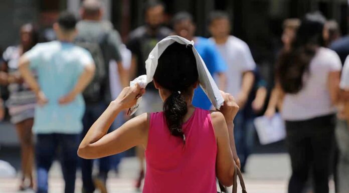 Una donna si protegge dal sole caldo mentre cammina in una strada del centro durante un'ondata di caldo estremo a San Paolo, in Brasile.