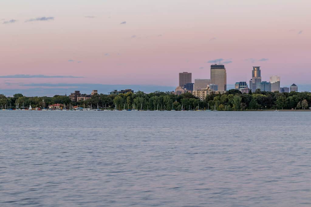 Uno scatto dello skyline di Minneapolis che si innalza sopra il lago Bde Maka Ska a South Minneapolis durante un crepuscolo estivo