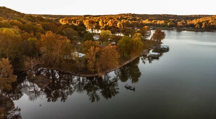 Pescatore che pesca dalla barca durante l'alba autunnale sul grande lago in oklahoma.  Foto scattata con drone