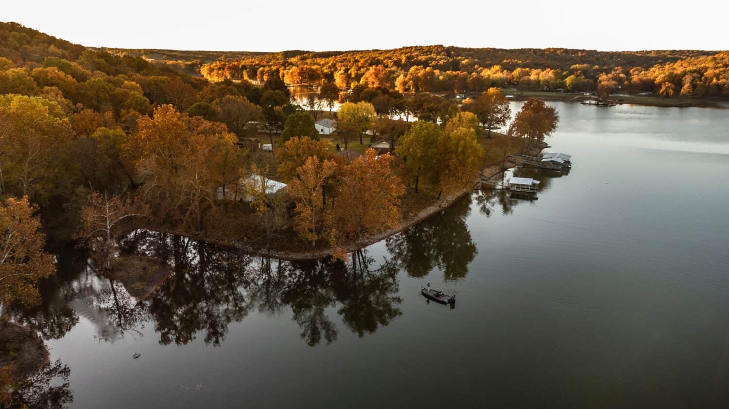 Pescatore che pesca dalla barca durante l'alba autunnale sul grande lago in oklahoma.  Foto scattata con drone