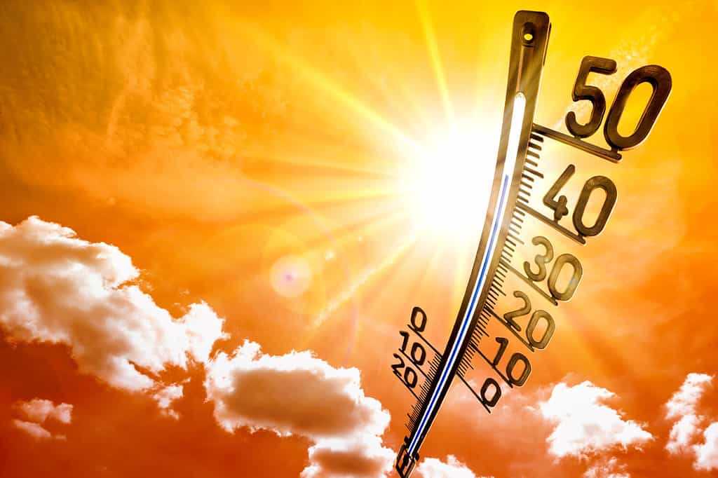 Estate calda o sfondo ondata di calore, sole splendente sul cielo arancione con termometro