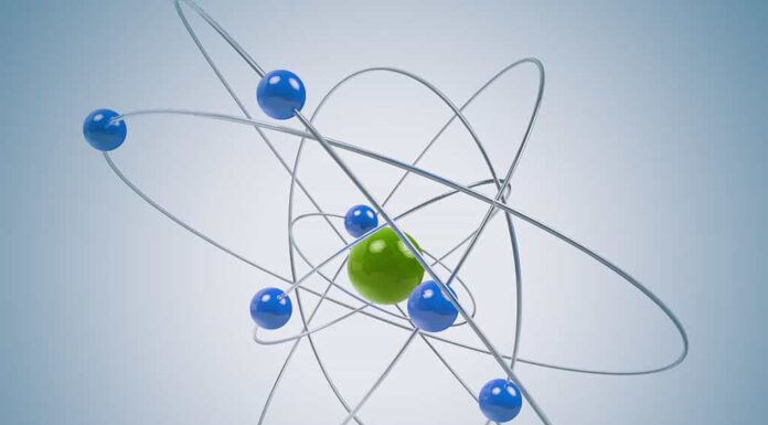Modello atomico 3D isolato con particelle verdi e blu.  Il nucleo centrale è circondato da una nuvola di elettroni caricati negativamente.