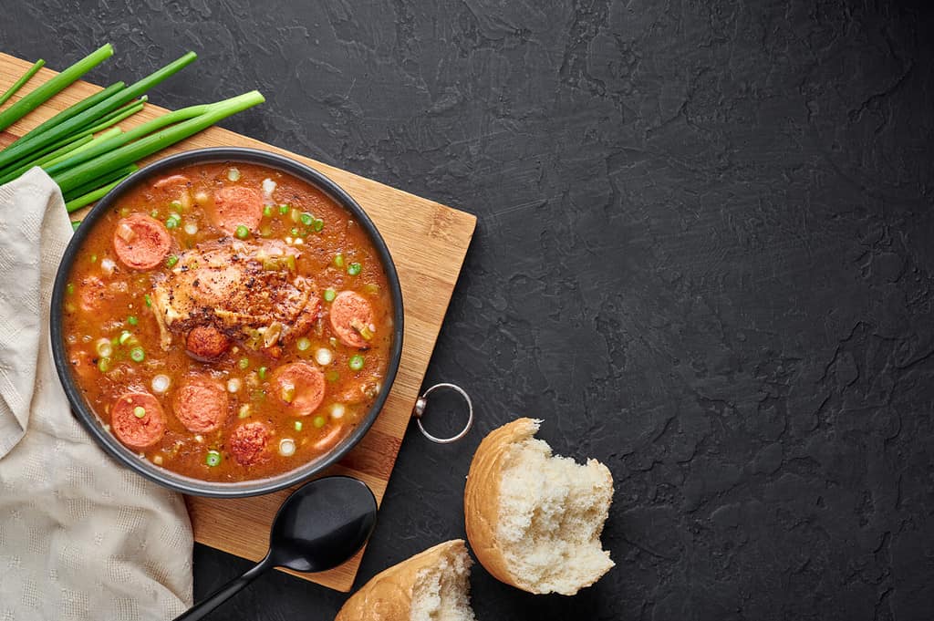 Zuppa di gumbo di pollo e salsiccia in ciotola nera su sfondo di ardesia scura.  Il gumbo è una zuppa della cucina cajun della Louisiana con roux.  Cibo americano USA.  Pasto etnico tradizionale.  Copia spazio