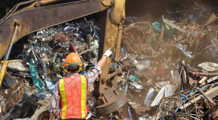 Industria del riciclaggio un lavoratore che ricicla cose nel centro di riciclaggio. Manager e lavoratore manuale in discarica di metalli