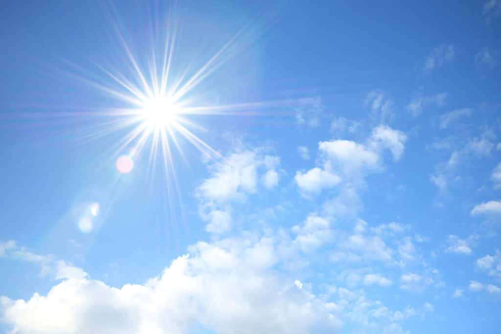 Cielo blu con soffici nuvole bianche e riflesso del sole.  Sfondo soleggiato.  Il sole appare direttamente sopra la Thailandia.  Il sole estivo pomeridiano risplende su un bel cielo con nuvole.  Tempo caldo, stagione estiva.