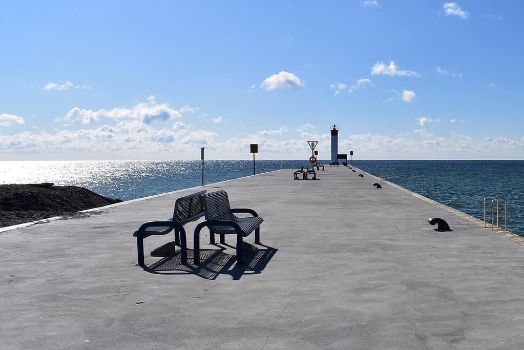 Vista in lontananza del faro con banchi vuoti lungo il molo di Whitby, Ontario, Canada in una bella giornata di sole