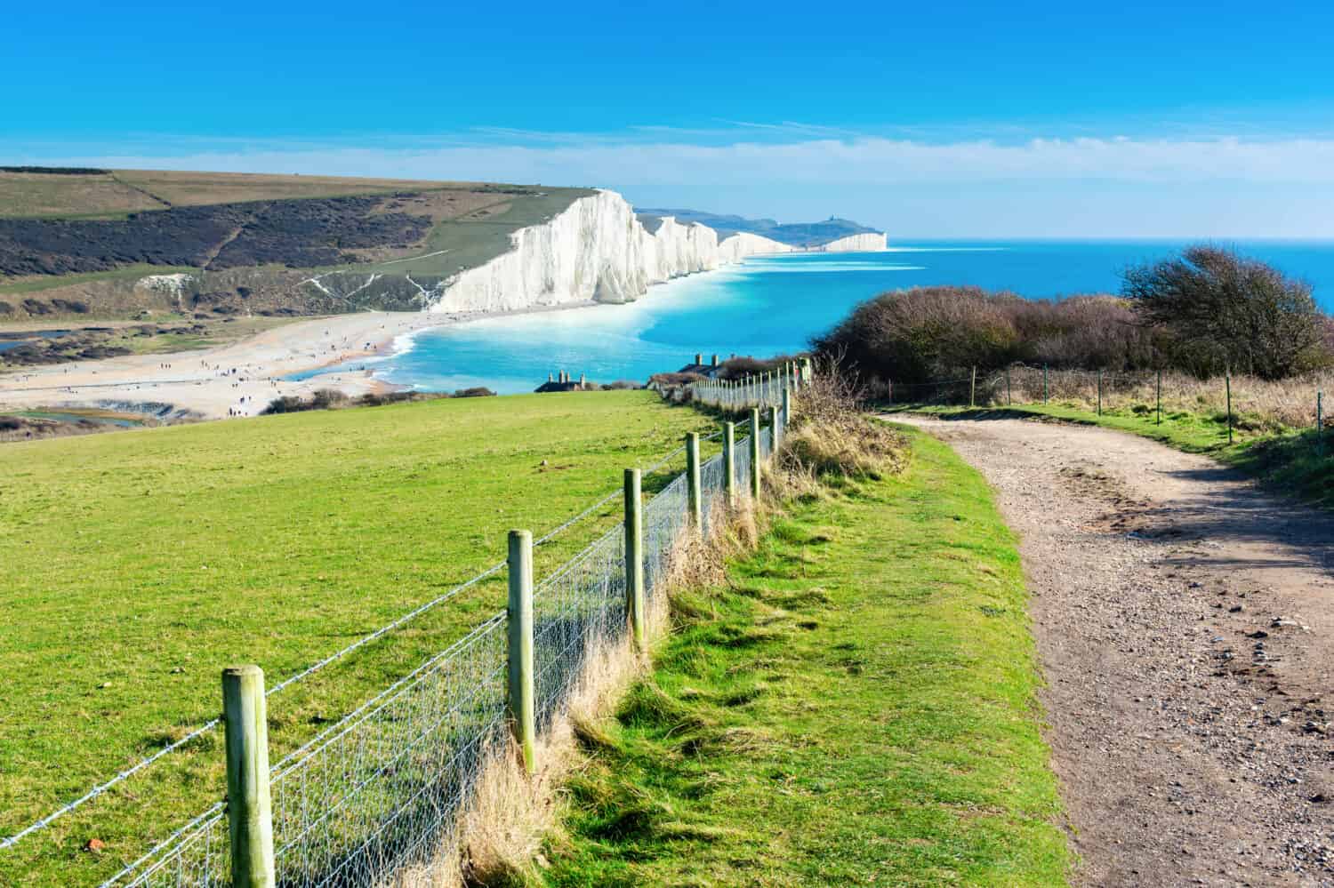 Passeggiata a Cuckmere Haven vicino a Seaford, East Sussex, Inghilterra.  Parco nazionale dei bassi del sud.  Vista del mare blu, scogliere, spiaggia, campi verdi, messa a fuoco selettiva