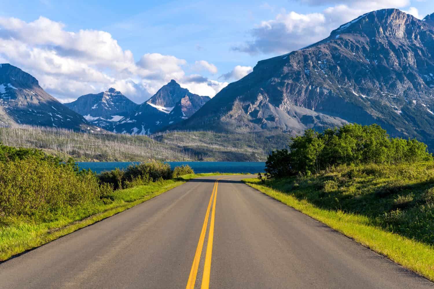 Go To The Sun Road - Una vista serale primaverile di una sezione est di Go To The Sun Road a Saint Mary Lake, con aspre vette alte che si stagliano sullo sfondo.  Parco nazionale dei ghiacciai.  Montana, USA. 