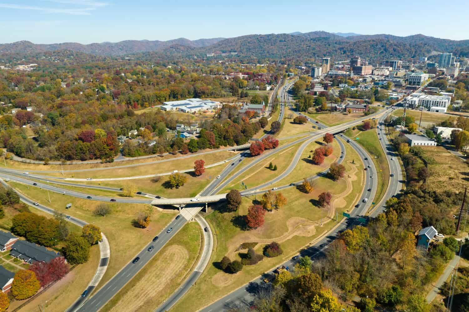 Vista aerea dell'intersezione della superstrada americana nella stagione autunnale ad Asheville, nella Carolina del Nord, con auto e camion in rapido movimento.  Concetto di infrastruttura di trasporto USA