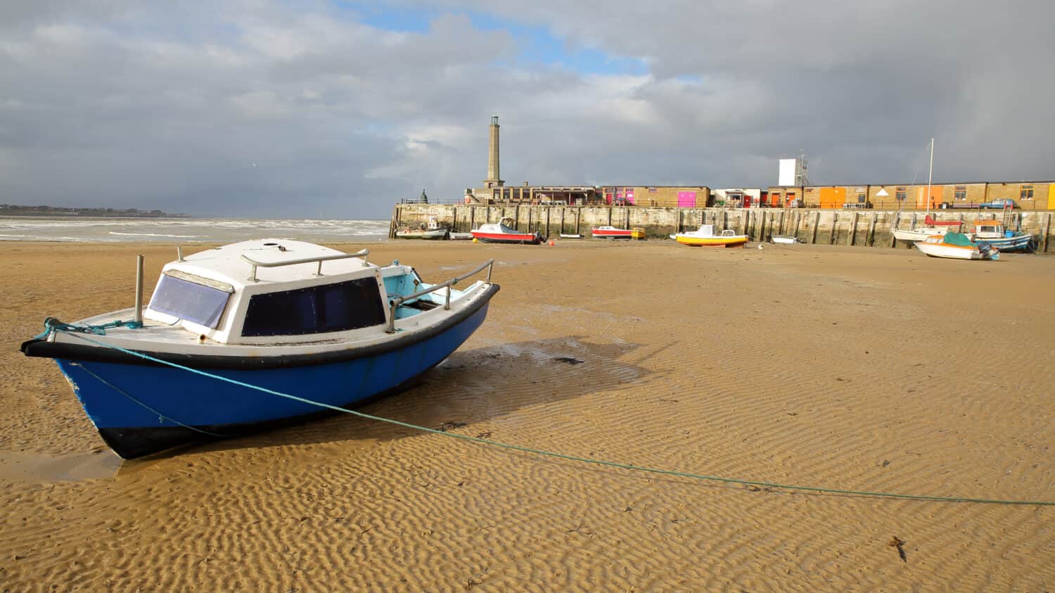 La spiaggia con la bassa marea con barche di ormeggio e Margate Harbour Arm in background, Margate, Kent, Regno Unito