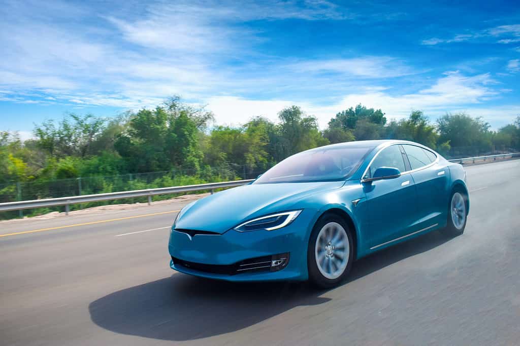 Un'auto elettrica di colore blu che gira sull'autostrada, con cielo blu chiaro. concetto di energia verde. Avere spazio per il testo.