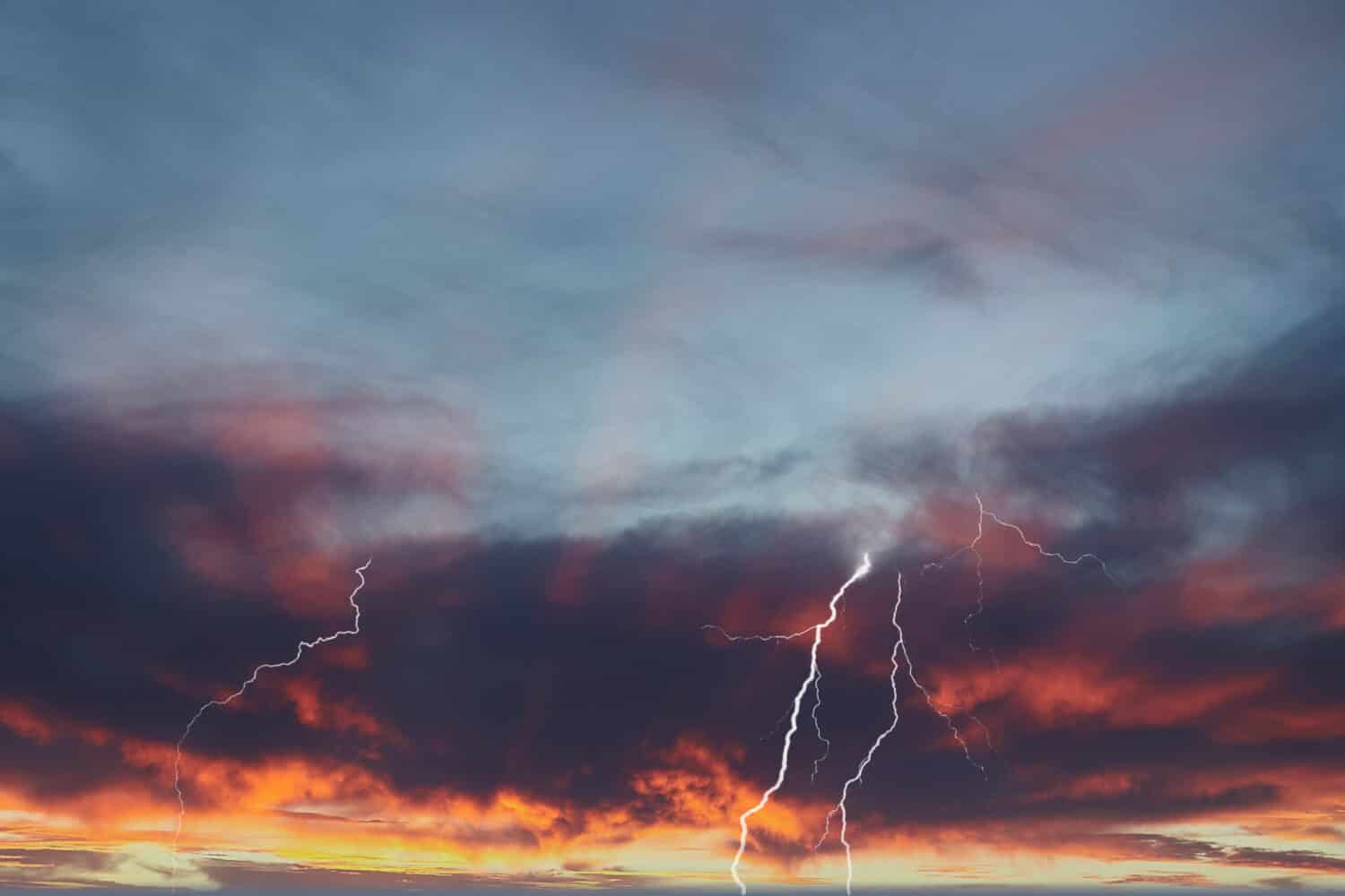 Fulmine quasi da nuvola a terra con tramonto rosso ardente e fulmini a nastro.