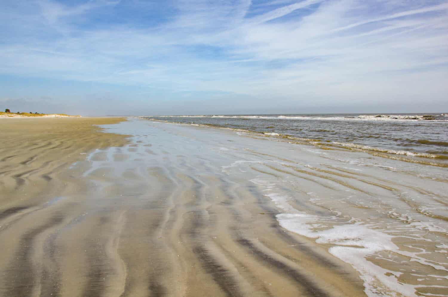 Una spiaggia senza persone.  Le dolci onde si infrangono sulla sabbia increspata di Sapelo Island, Carolina del Sud.
