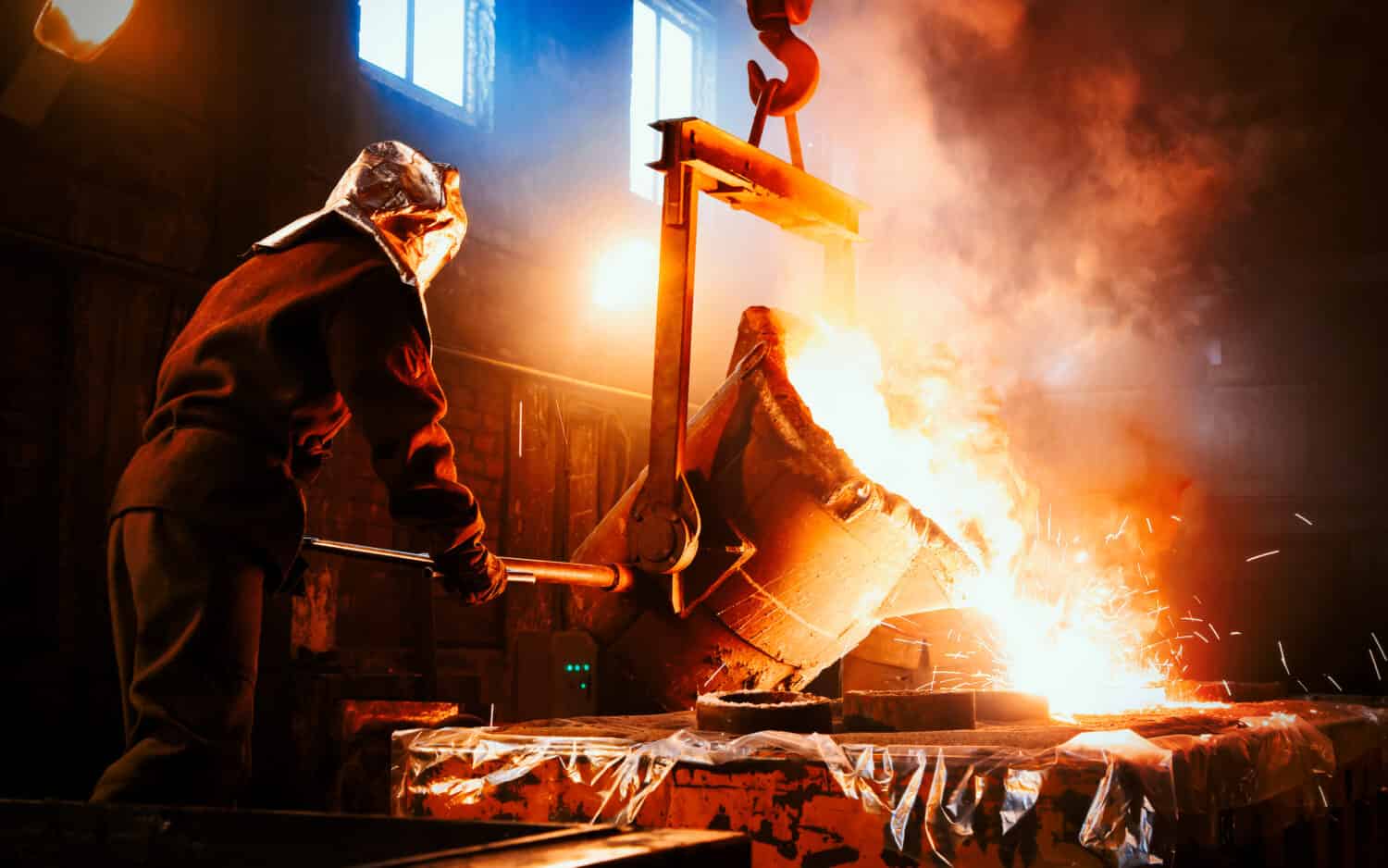 I lavoratori opera presso l'impianto metallurgico.  Il metallo liquido viene versato negli stampi.  Operaio che controlla la fusione dei metalli nei forni.
