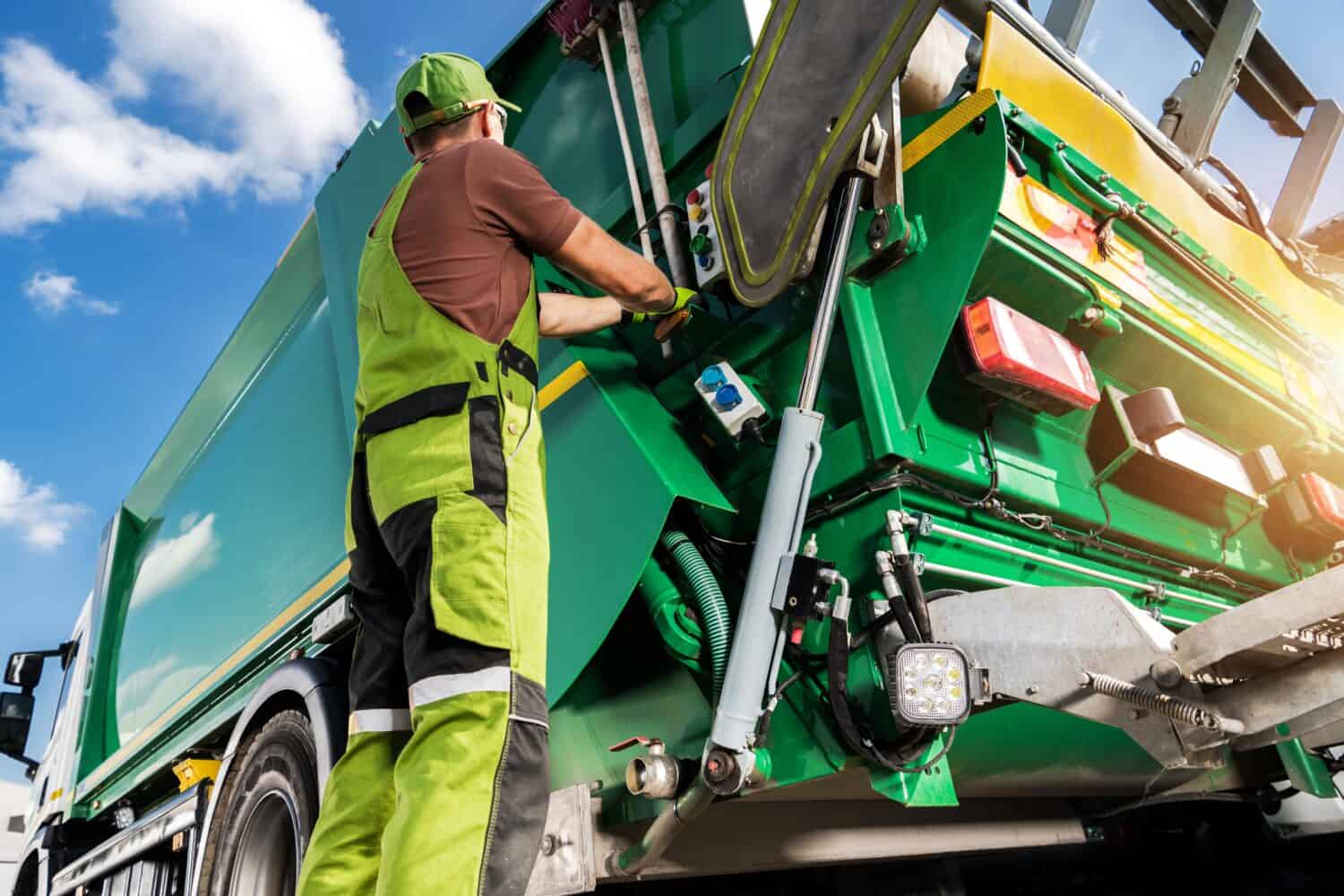 Camion della spazzatura moderno e operaio raccoglitore di rifiuti caucasico.  Tema di raccolta differenziata e gestione dei rifiuti.