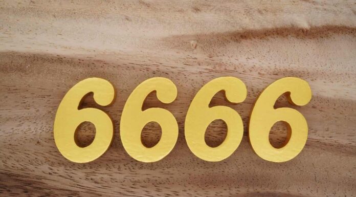 Numeri in legno 6666 dipinti in oro su uno sfondo di tavole fantasia marrone scuro e bianco.