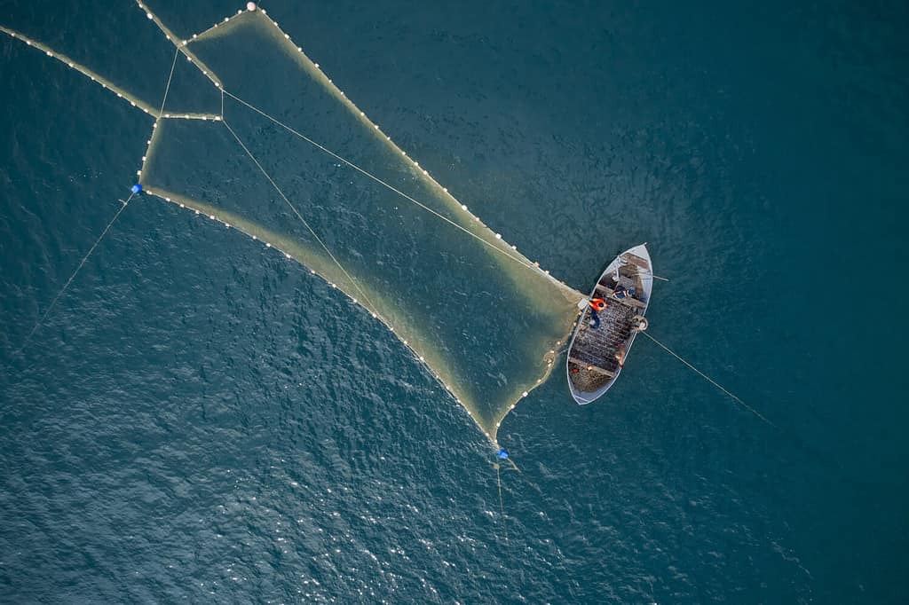 Barca di legno d'epoca nel Mar dei Coralli.  Foto drone barca.  Un pescatore su un peschereccio lancia una rete per pescare.
