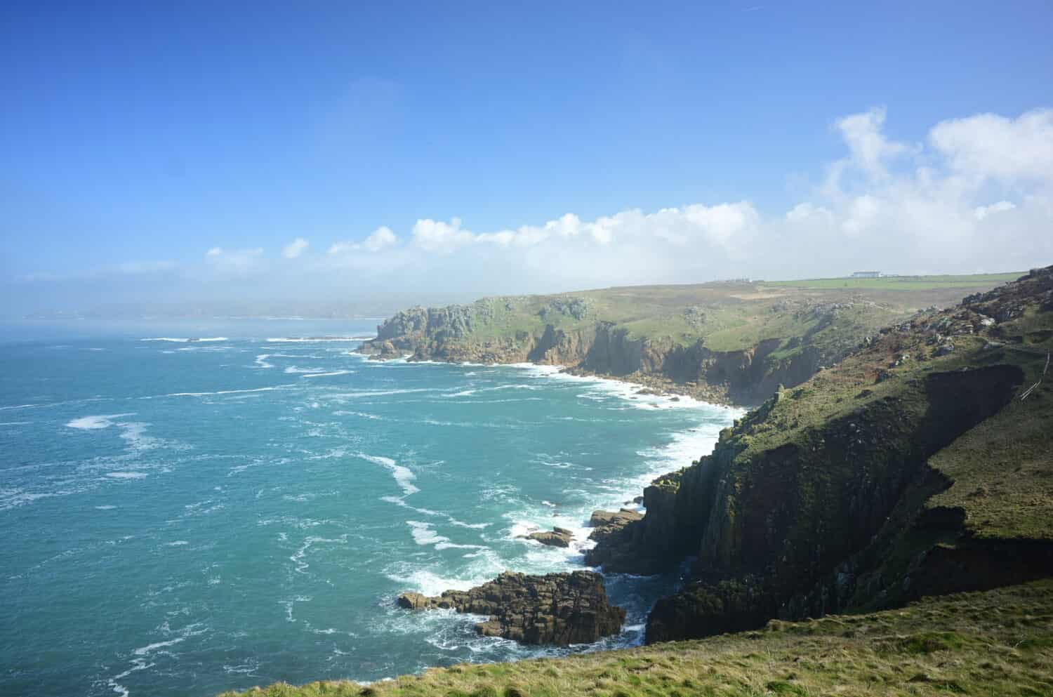 Il Land's End sotto la luce del sole e un cielo blu durante il giorno nella Cornovaglia occidentale in Inghilterra