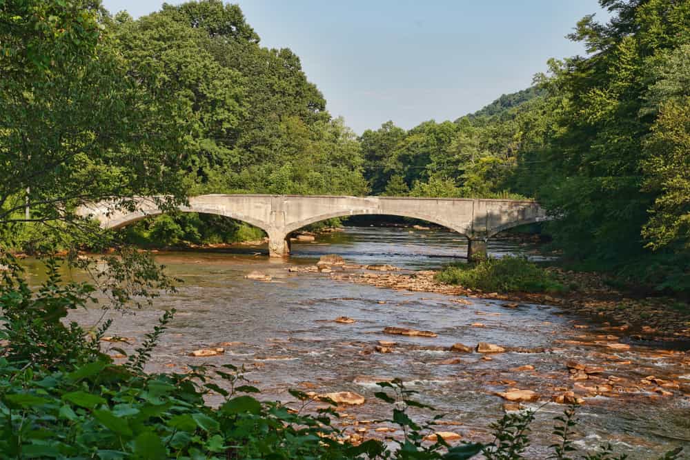 Ponte ad arco abbandonato, in cemento, lungo il Ghost Town Trail nella Pennsylvania occidentale.  Immagine di sfondo scenico.  Rotaie ai sentieri.  Sentieri di Allegheny. 