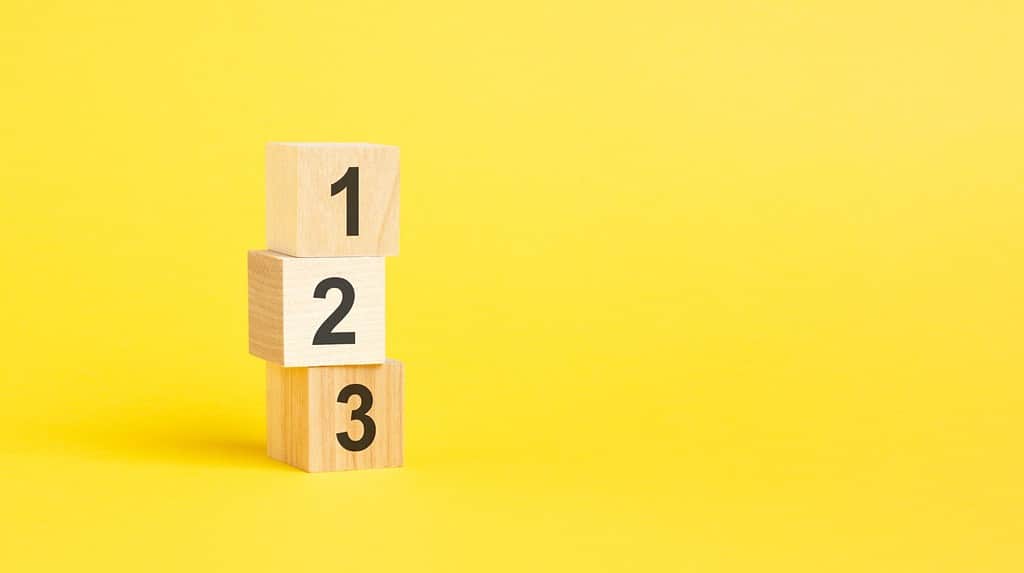 numeri 123 su cubi di legno in piedi uno sopra l'altro, sfondo giallo