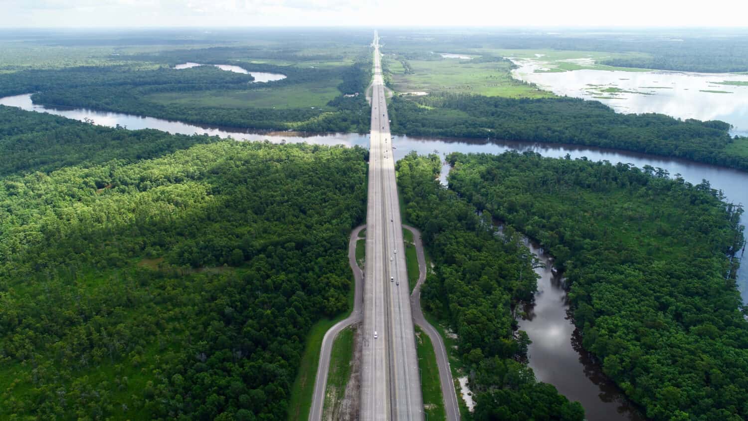 Autostrada trafficata circondata da alberi e dallo splendido fiume Sabine, sinuoso.  Questo fiume è al confine tra Texas e Louisiana.