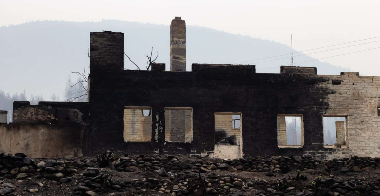 Detriti di fuoco di case in una piccola città con fumo nel cielo.  Causato da incendi boschivi a Lytton, British Columbia, Canada.