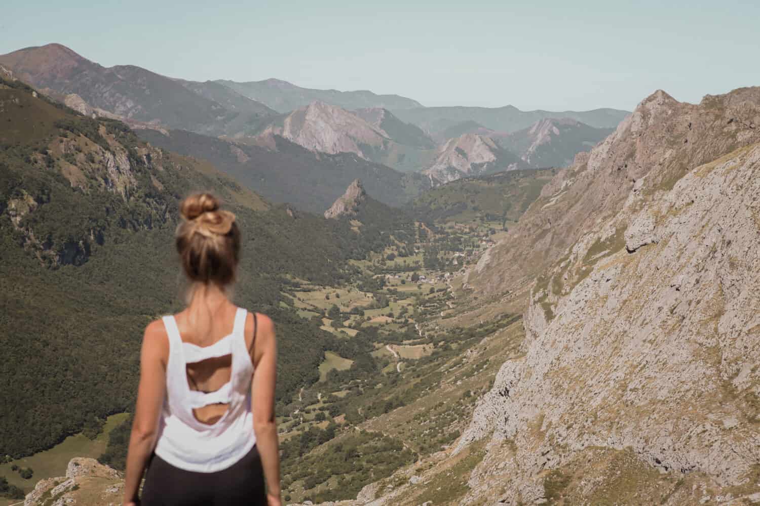 Giovane donna seduta sulla roccia guardando il bellissimo paesaggio del parco naturale di Somiedo nelle Asturie, Spagna, valle di montagna