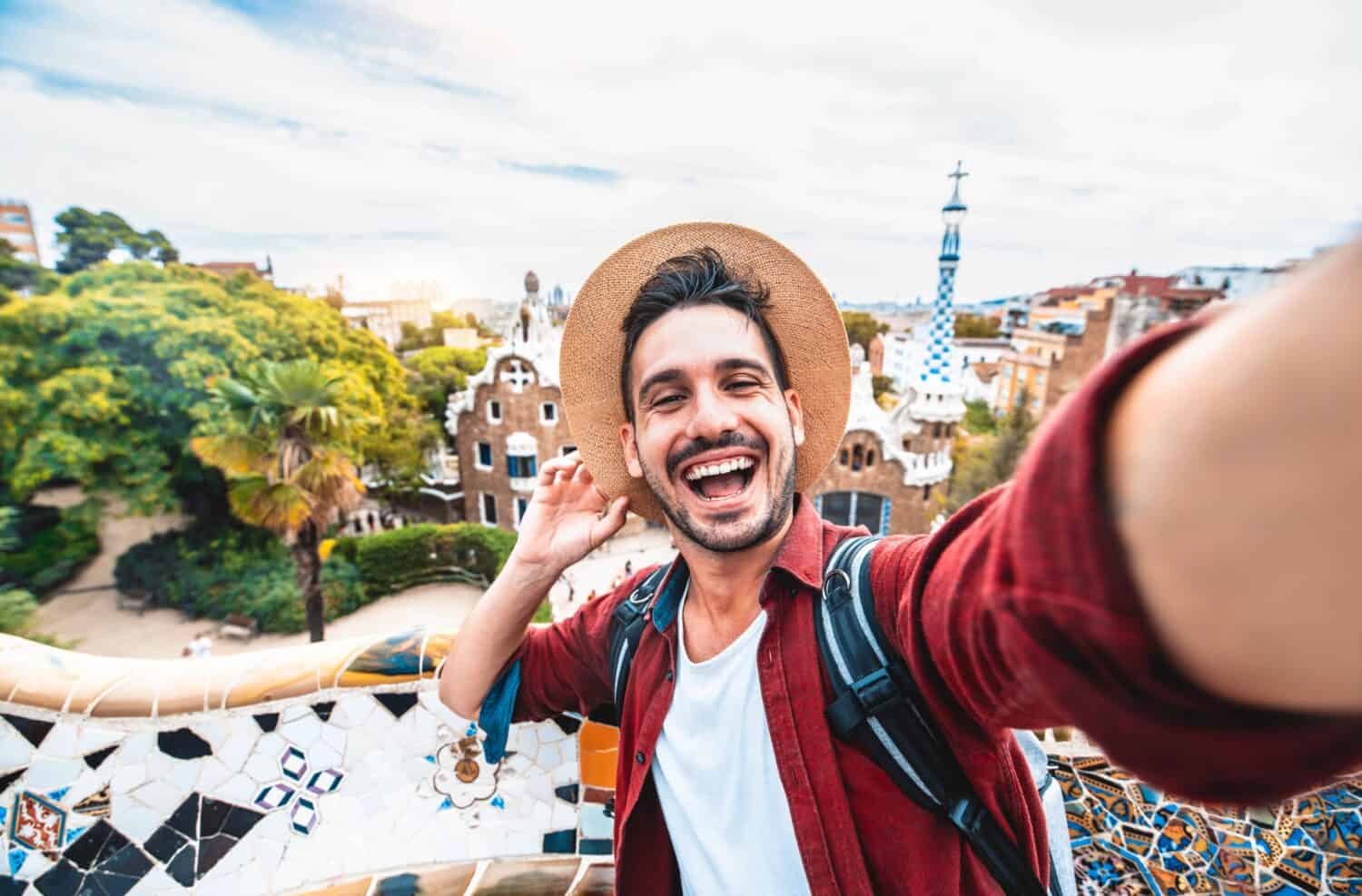 Un turista felice si scatta un autoritratto selfie con lo smartphone nel Parco Guell, Barcellona, ​​Spagna - Uomo sorridente in vacanza che guarda l'obbiettivo - Vacanze e concetto di viaggio