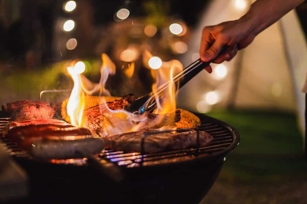 Famiglia che fa barbecue durante la cena in campeggio di notte