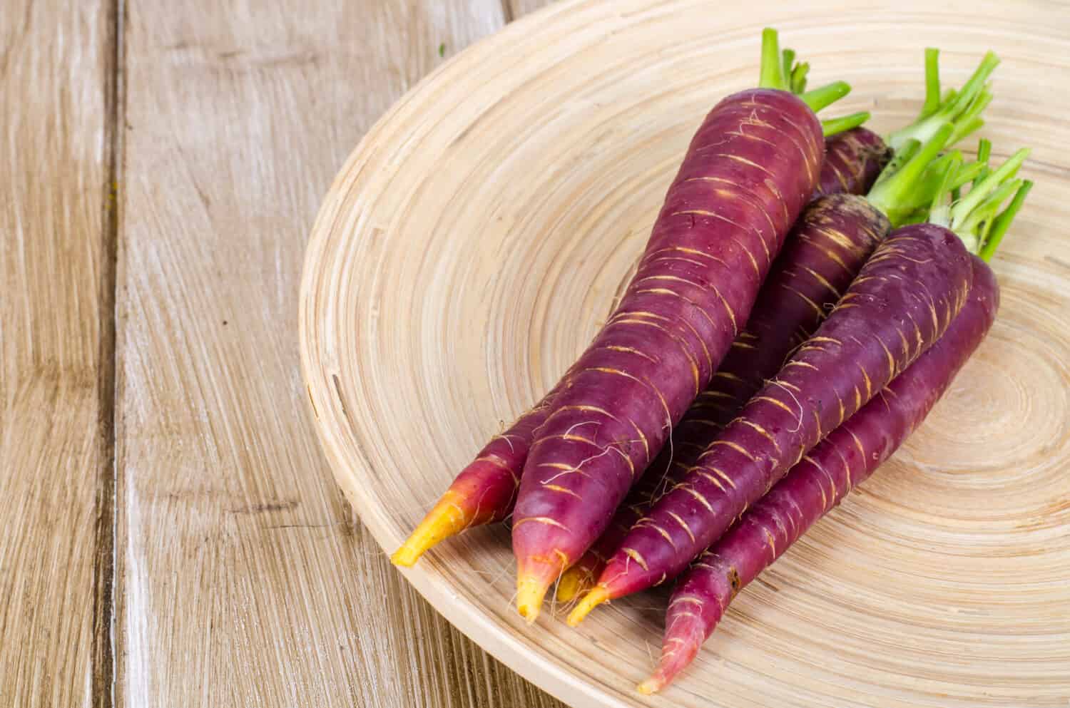 Carota viola affettata su fondo di legno.  Foto in studio 