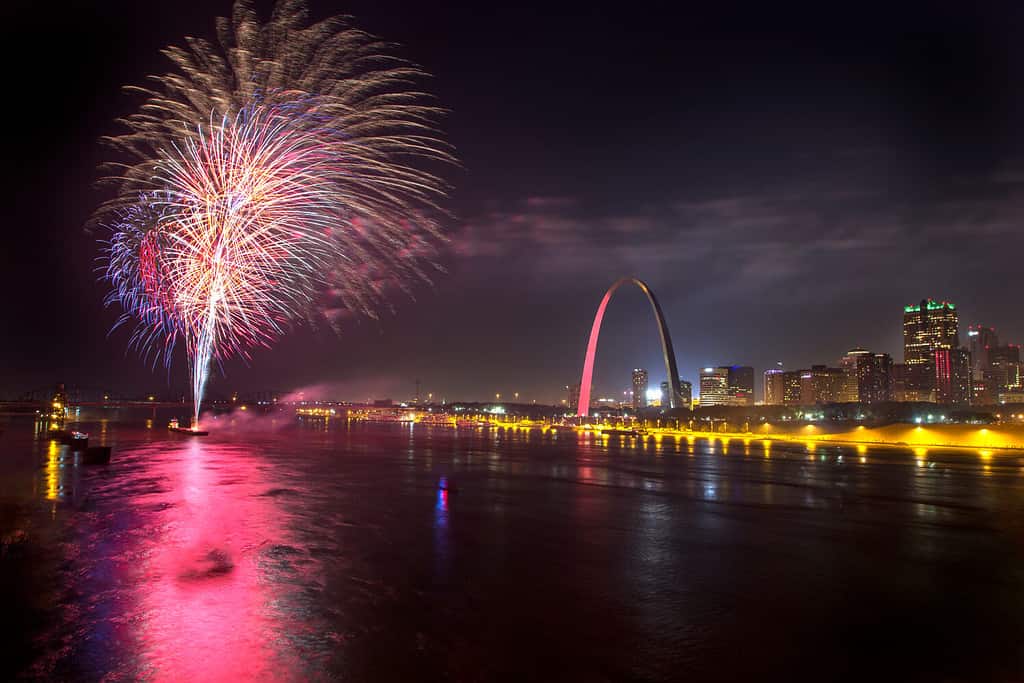 Fuochi d'artificio colorati esplodono nel cielo notturno sopra il fiume Mississippi e l'arco di accesso a St Louis durante la celebrazione del 4 luglio