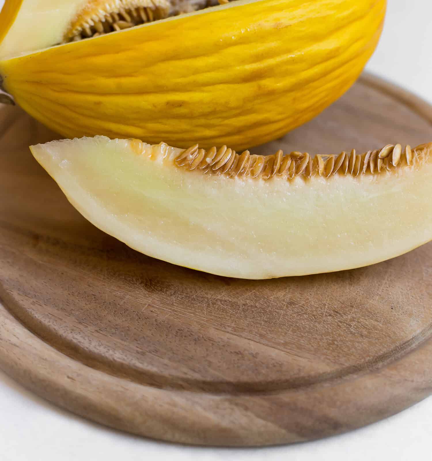 melone canarino su una tavola di legno e uno sfondo bianco